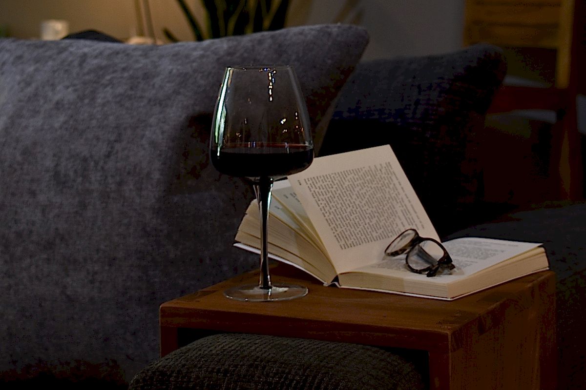 Book on teak armrest with glass of red wine